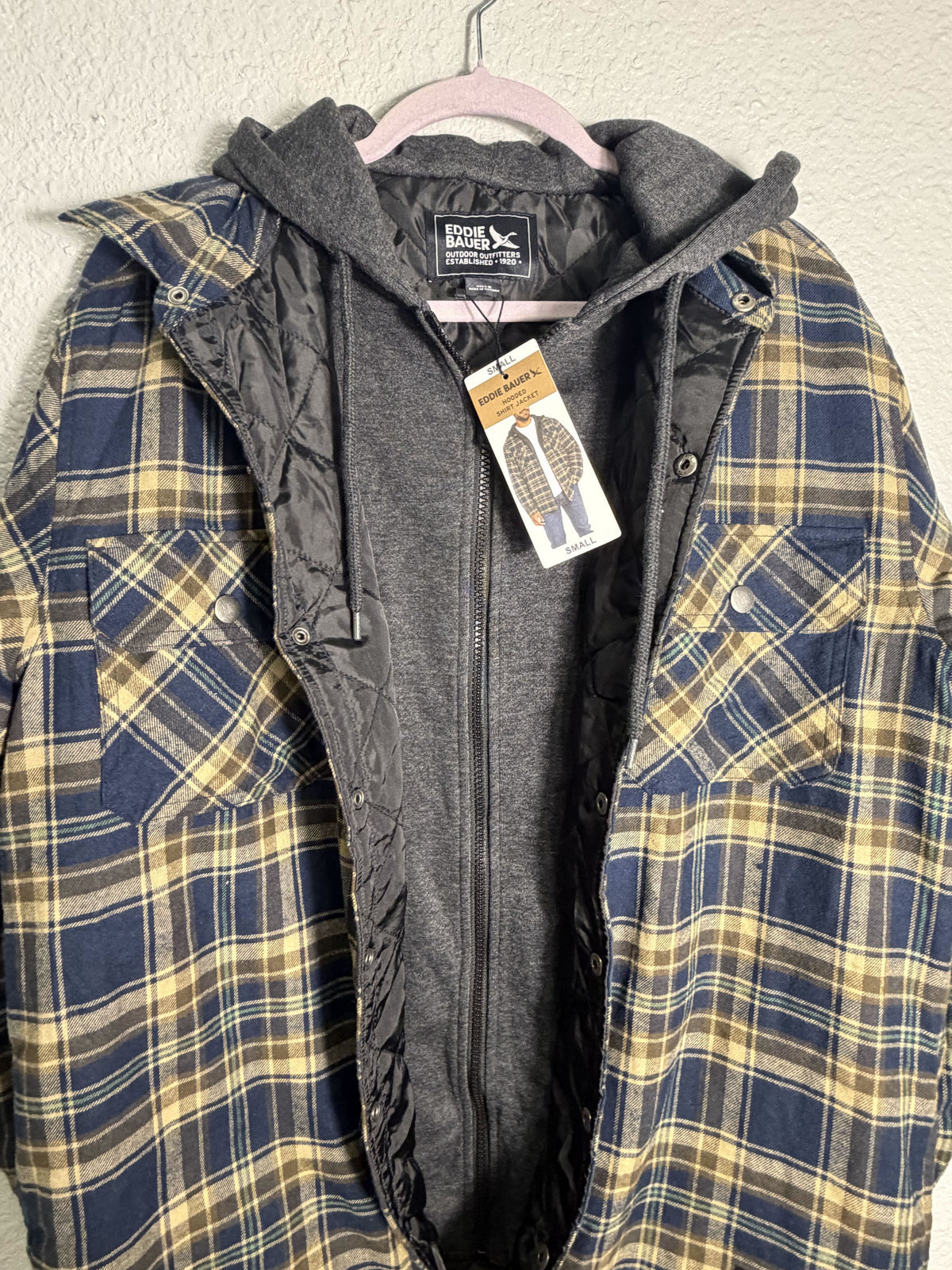 Eddie Bauer men's navy and tan plaid hooded flannel shirt jacket with quilted lining, size small, displayed on a hanger.
