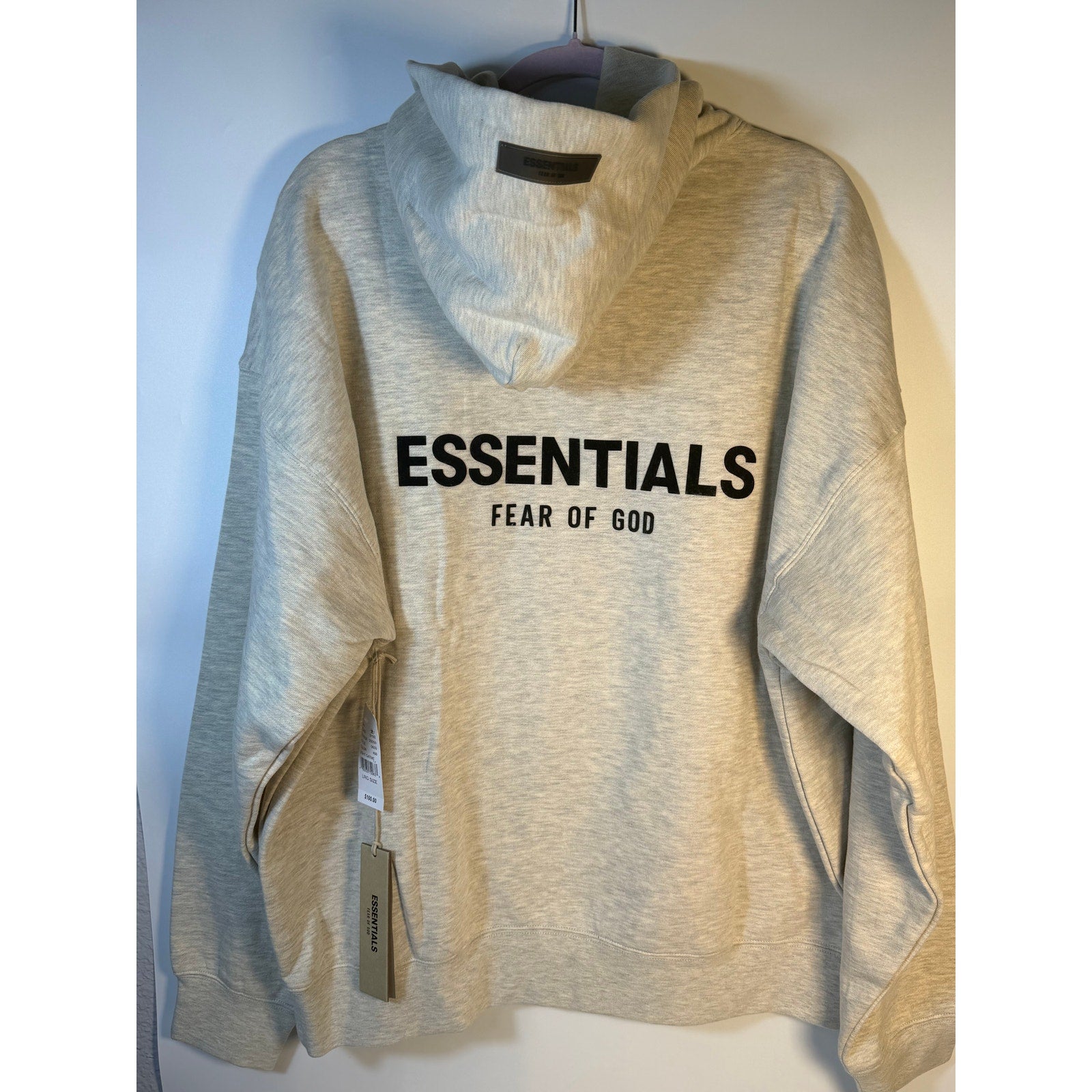 Fear of God ESSENTIALS men's light oatmeal pullover hoodie with logo, casual sweatshirt, front view showing fabric texture and fit.