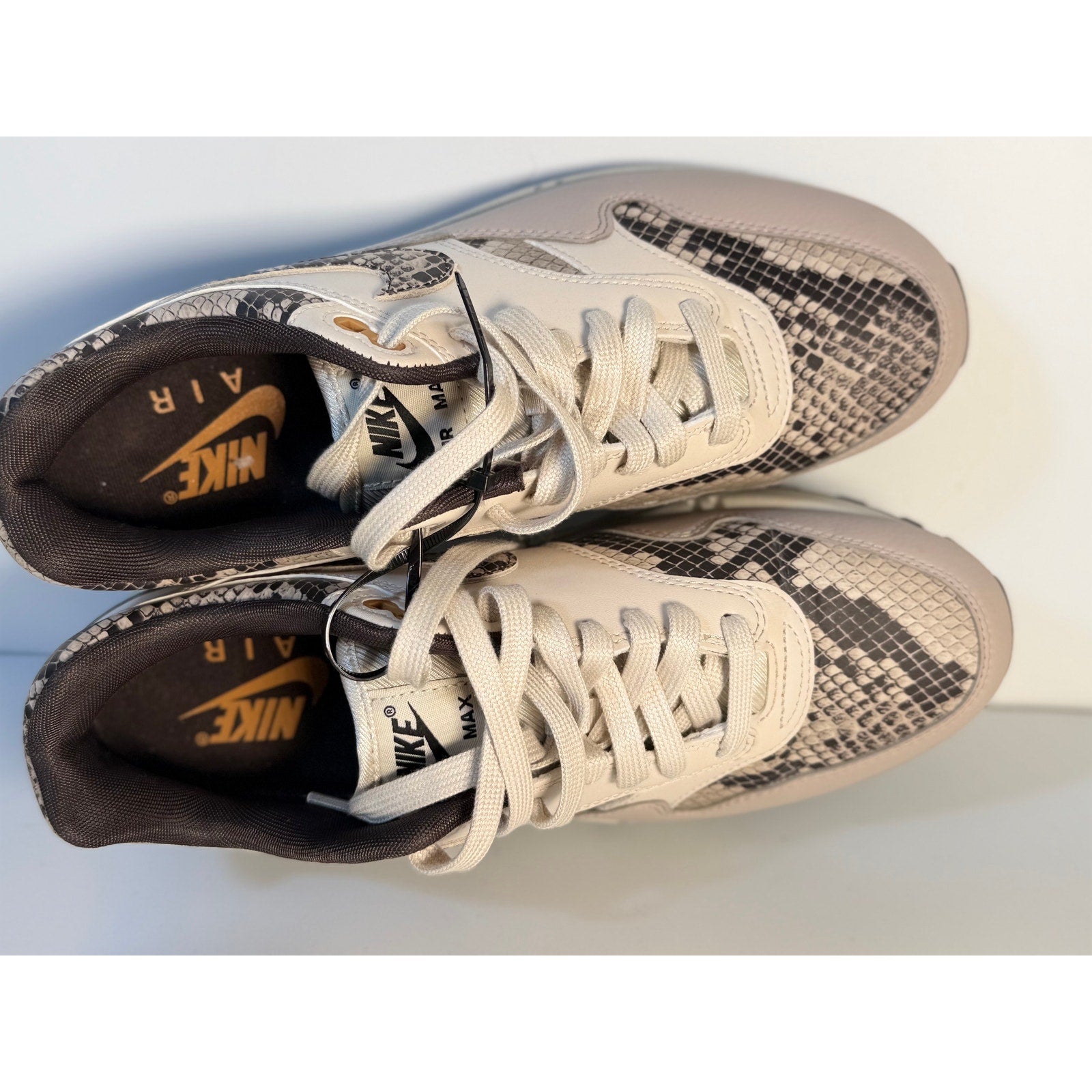 Nike Air Max 1 Premium Snakeskin sneakers in white and gray for women, featuring textured snakeskin pattern and sporty design.