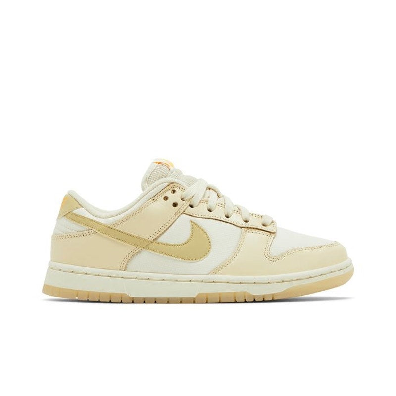 Nike Dunk Low women's sneakers in gold and white with a low-top design, featuring Nike branding and white laces.