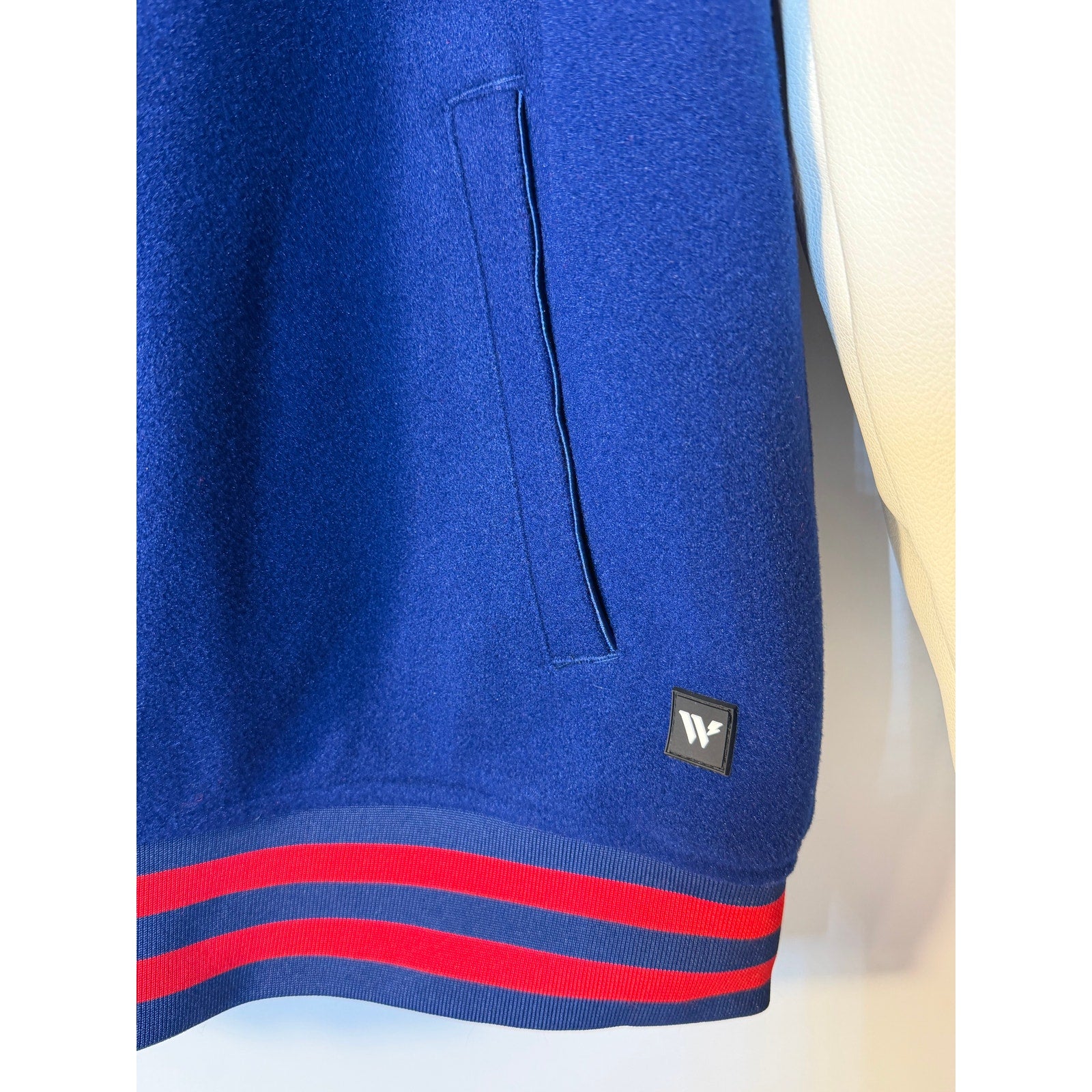 New York Giants women's varsity hooded jacket in blue and white by The Wild Collective, featuring team logo and varsity style.