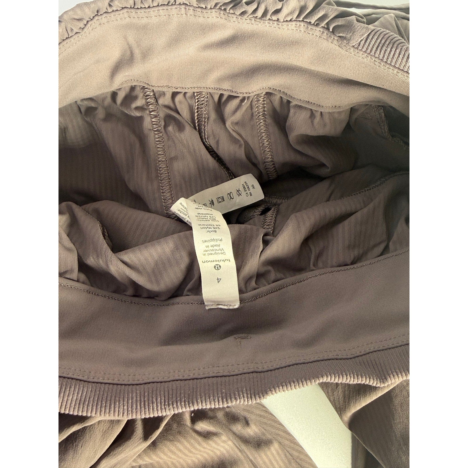 Lululemon women's taupe gray high-rise ruched tapered pants, size 4, preowned, showing the fitted waistband and tapered leg design.