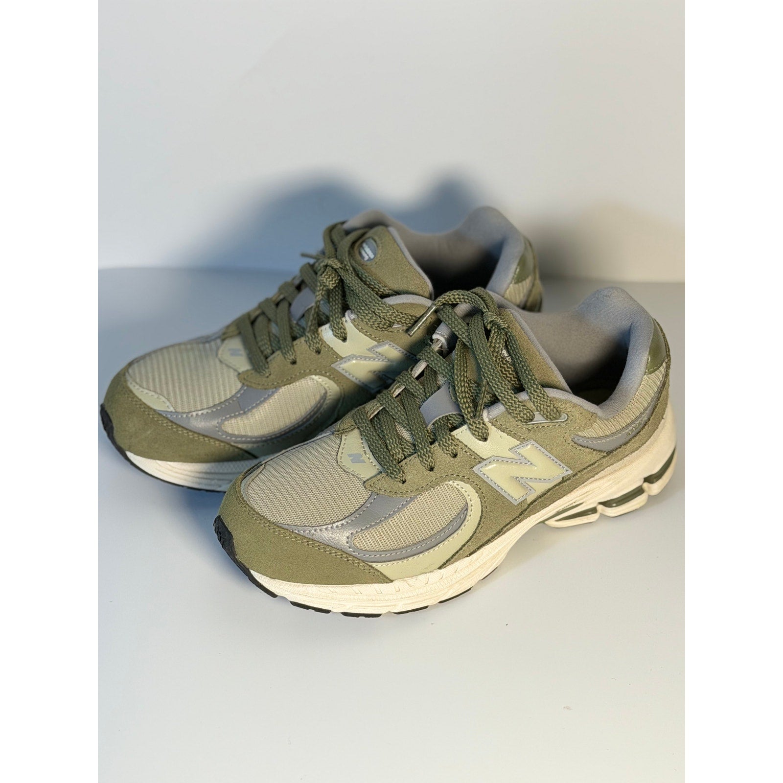 Pre-owned New Balance 2002R athletic running sneakers in olive and gray for youth size 5.5, featuring breathable mesh and supportive design.