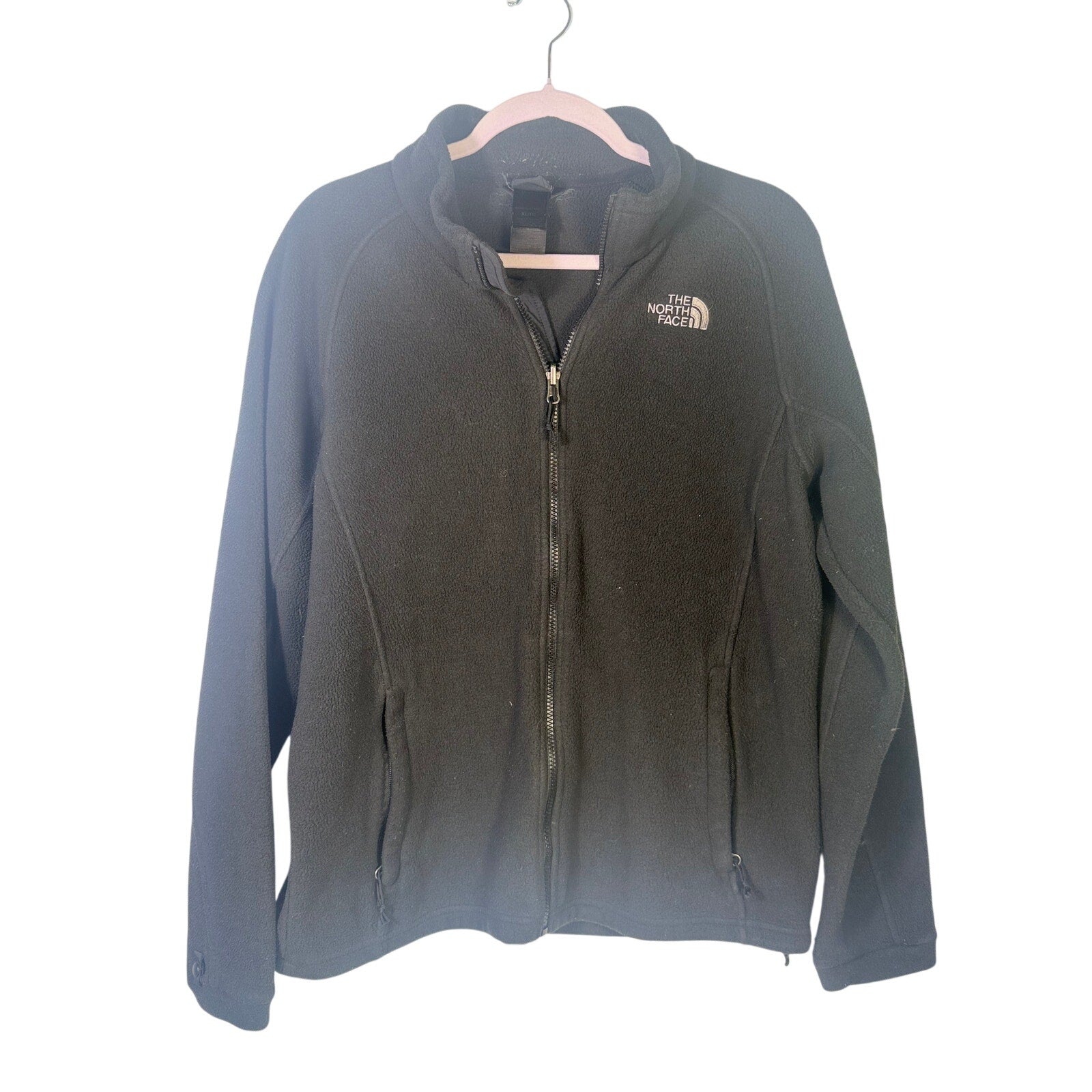 The North Face women's black full-zip fleece jacket with outdoor logo, featuring a stand-up collar and zippered pockets.
