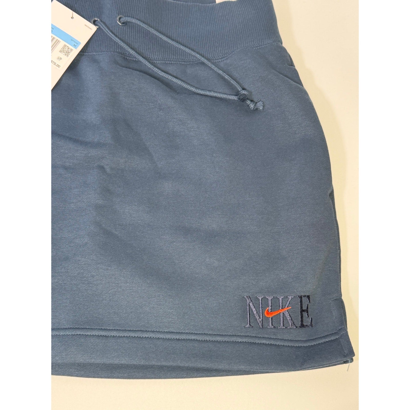 Nike women's navy blue fleece drawstring mini skirt, size M, showing the front view with elastic waistband and Nike logo detail.