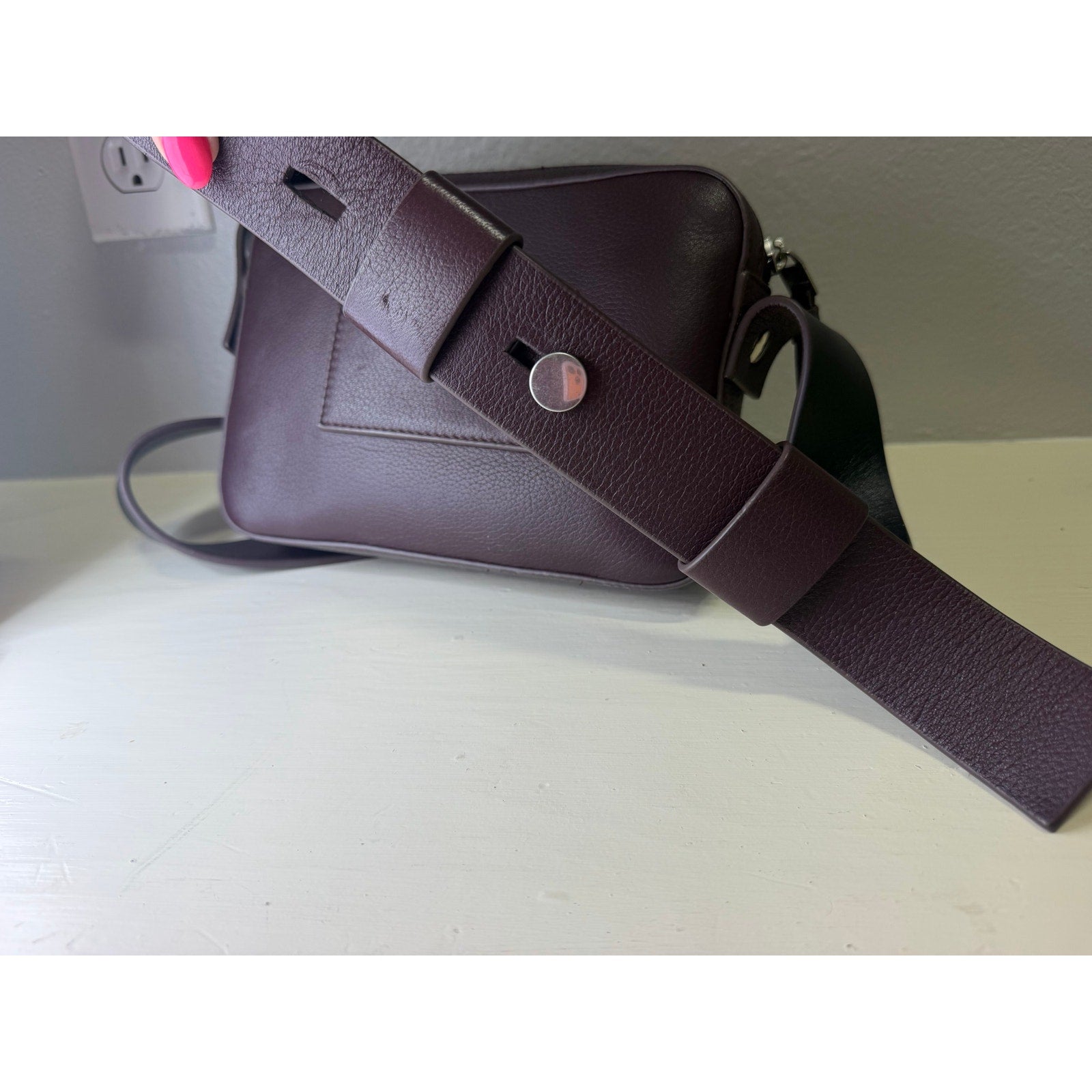 AllSaints women's burgundy pebbled leather camera crossbody bag with adjustable strap, featuring a stylish handbag design.