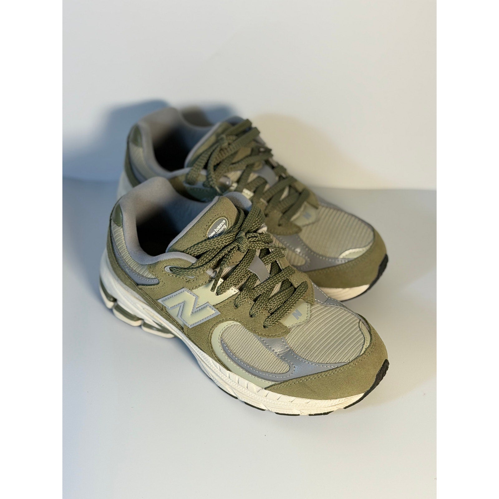 Pre-owned New Balance 2002R athletic running sneakers in olive and gray for youth size 5.5, showing the side view of the shoes.