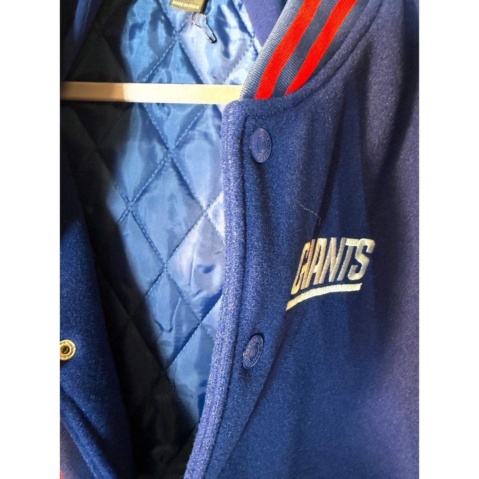 New York Giants women's varsity hooded jacket in blue and white by The Wild Collective, featuring team logo and athletic style.