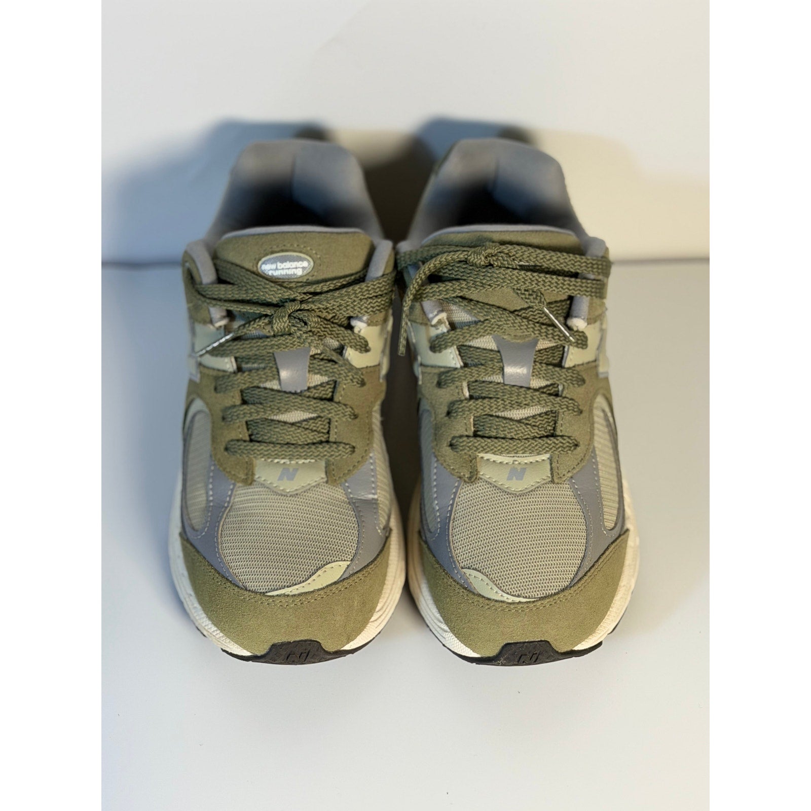 Pre-owned New Balance 2002R athletic sneakers for youth, olive and gray color, size 5.5, showing side view of the shoes.