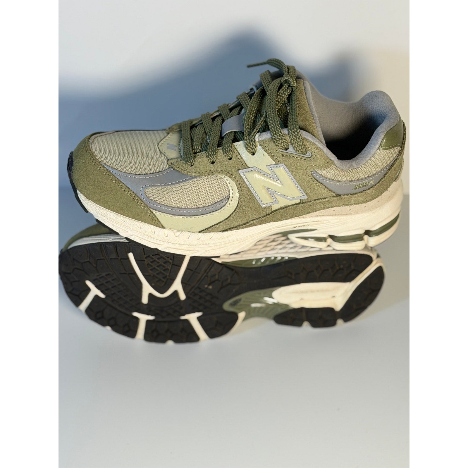 Pre-owned New Balance 2002R athletic running sneakers in olive and gray for youth size 5.5, showing side view of the shoes.