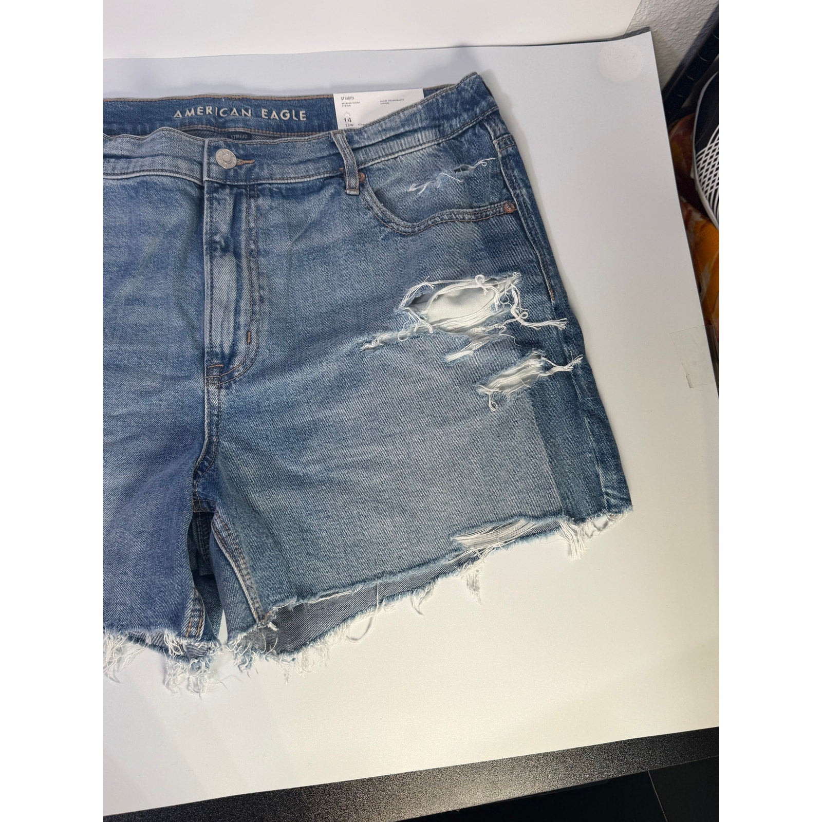 American Eagle women's distressed high-rise denim shorts in size 14, relaxed fit, with frayed hems and classic five-pocket style.