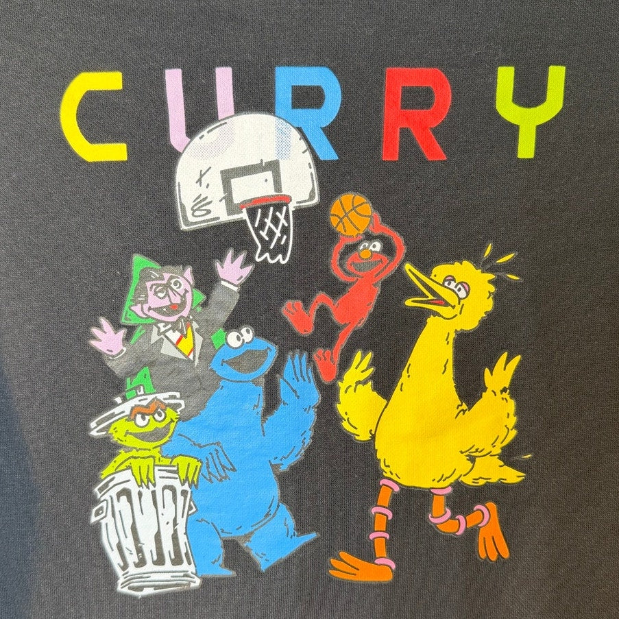 Youth black Under Armour Curry Sesame Street crewneck sweatshirt with colorful Sesame Street design and Under Armour logo.