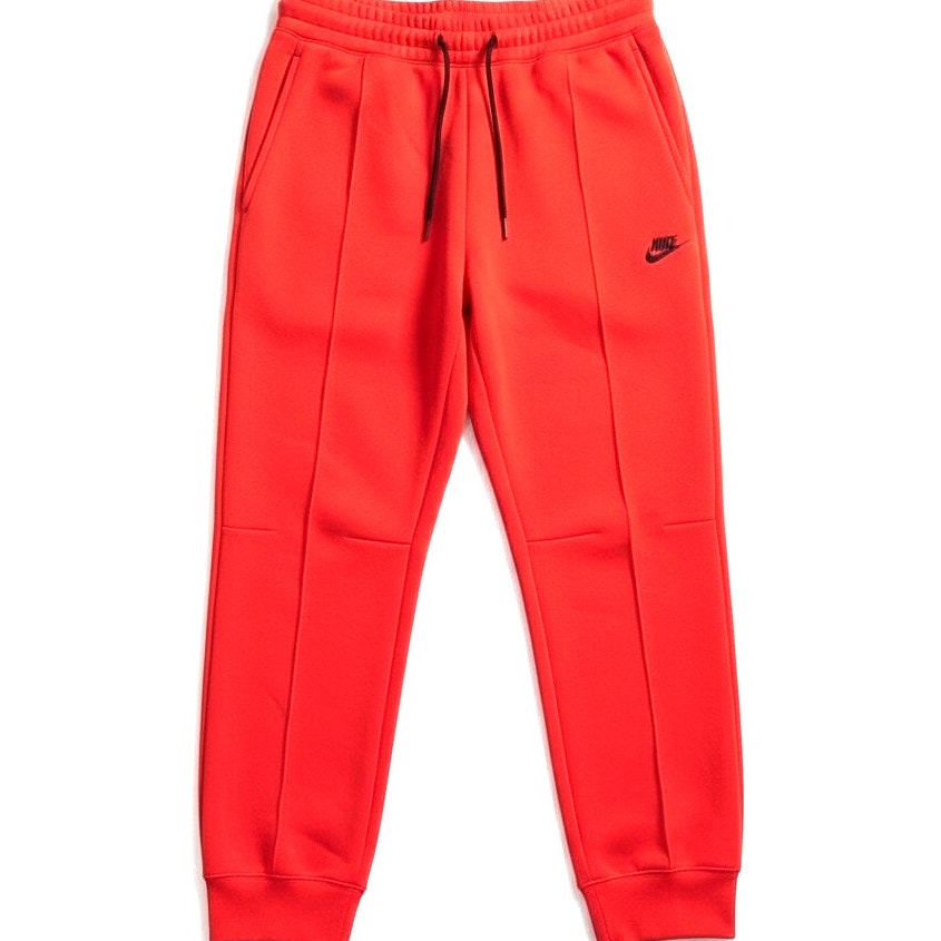 Women's orange Nike Sportswear Tech Fleece joggers with elastic waistband and tapered fit, displayed on a plain background.