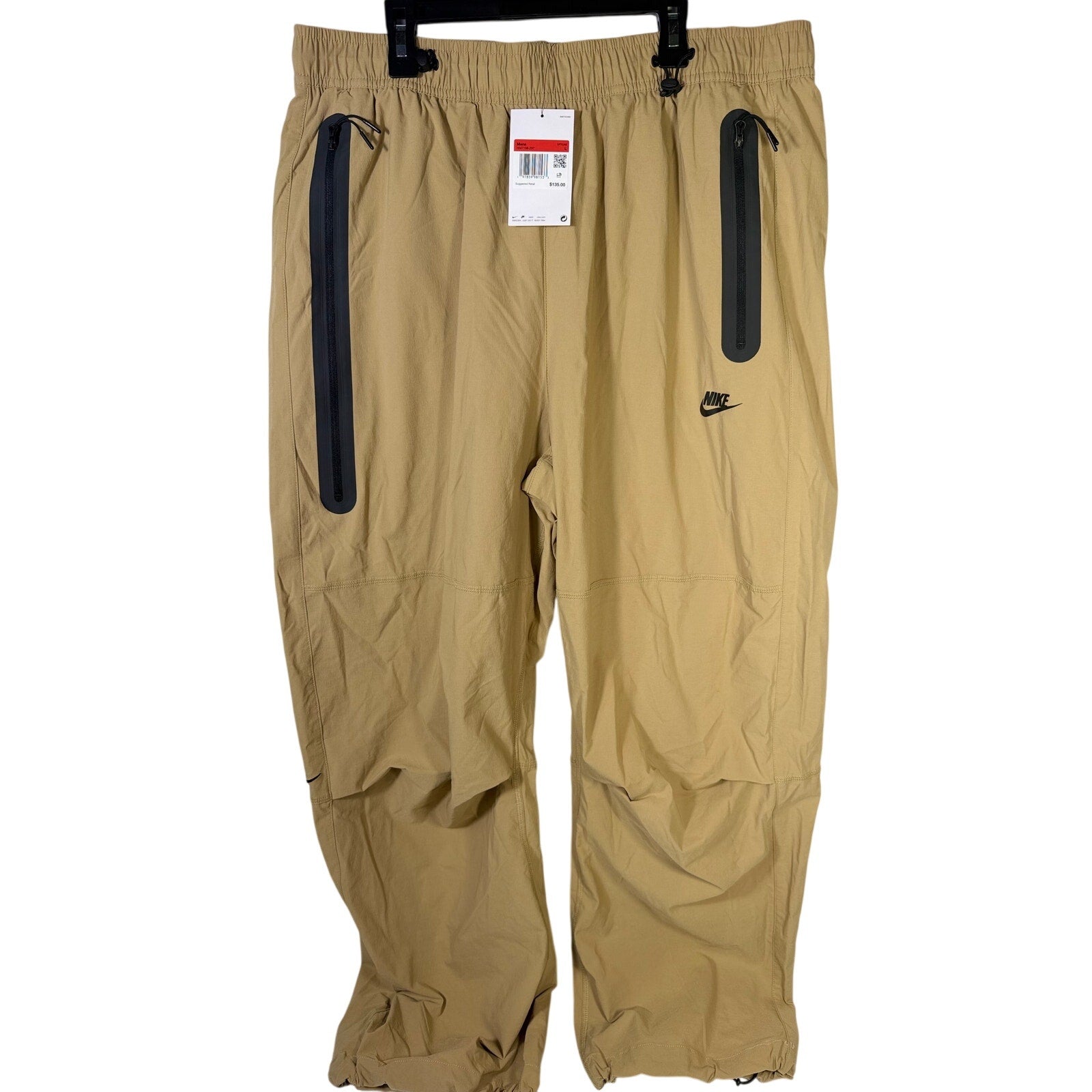 Nike Tech men's woven oversized parachute beige pants, size L, with relaxed fit and lightweight fabric.