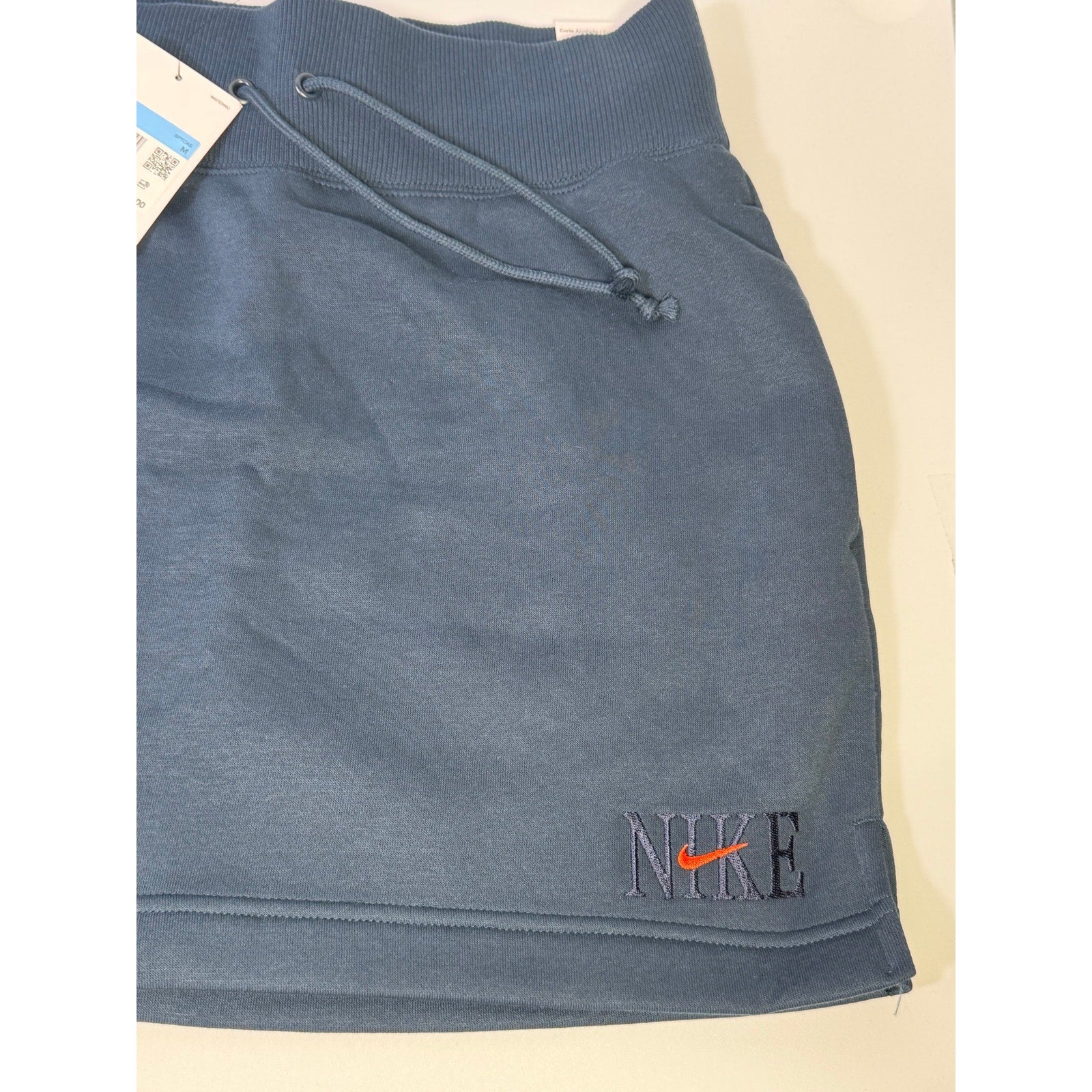 Nike women's navy blue fleece drawstring mini skirt, size M, showing front view with waistband and casual style.