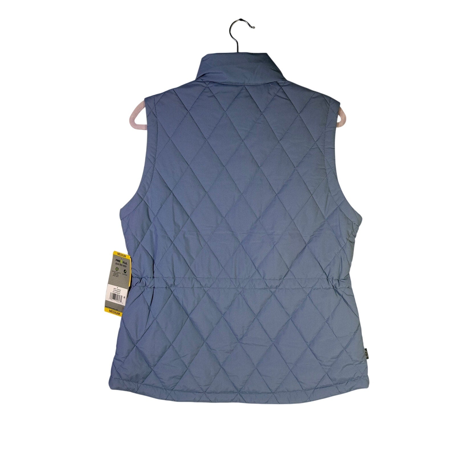 Free Country women's FreeCycle quilted vest in stonewash blue, size M, displayed on a hanger with a quilted pattern and stand-up collar.