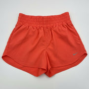 Nike women's coral training shorts, high-waisted Dri-FIT athletic shorts in size XL, shown on a model with a sporty background.