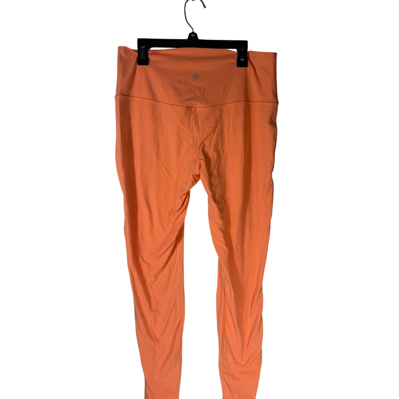 Lululemon women's high-rise burnt orange leggings size 12, close-up of fitted athletic leggings with Lululemon logo.