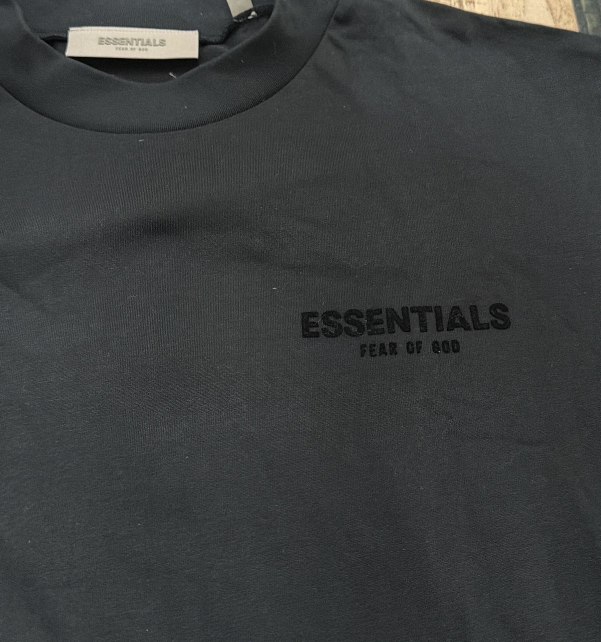 Black Essentials Fear of God logo T-shirt for men, size M, featuring a minimalist design and brand logo on the front.