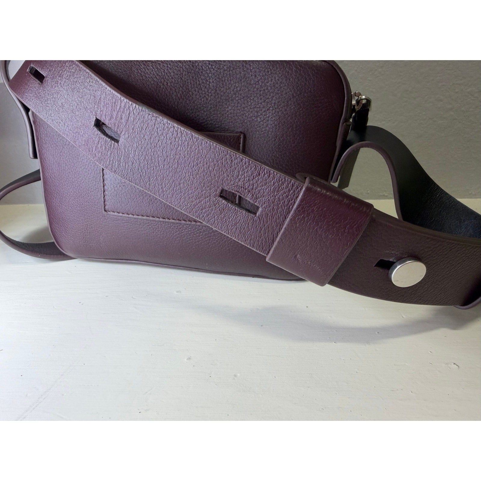 AllSaints women's burgundy pebbled leather camera crossbody handbag with adjustable strap.