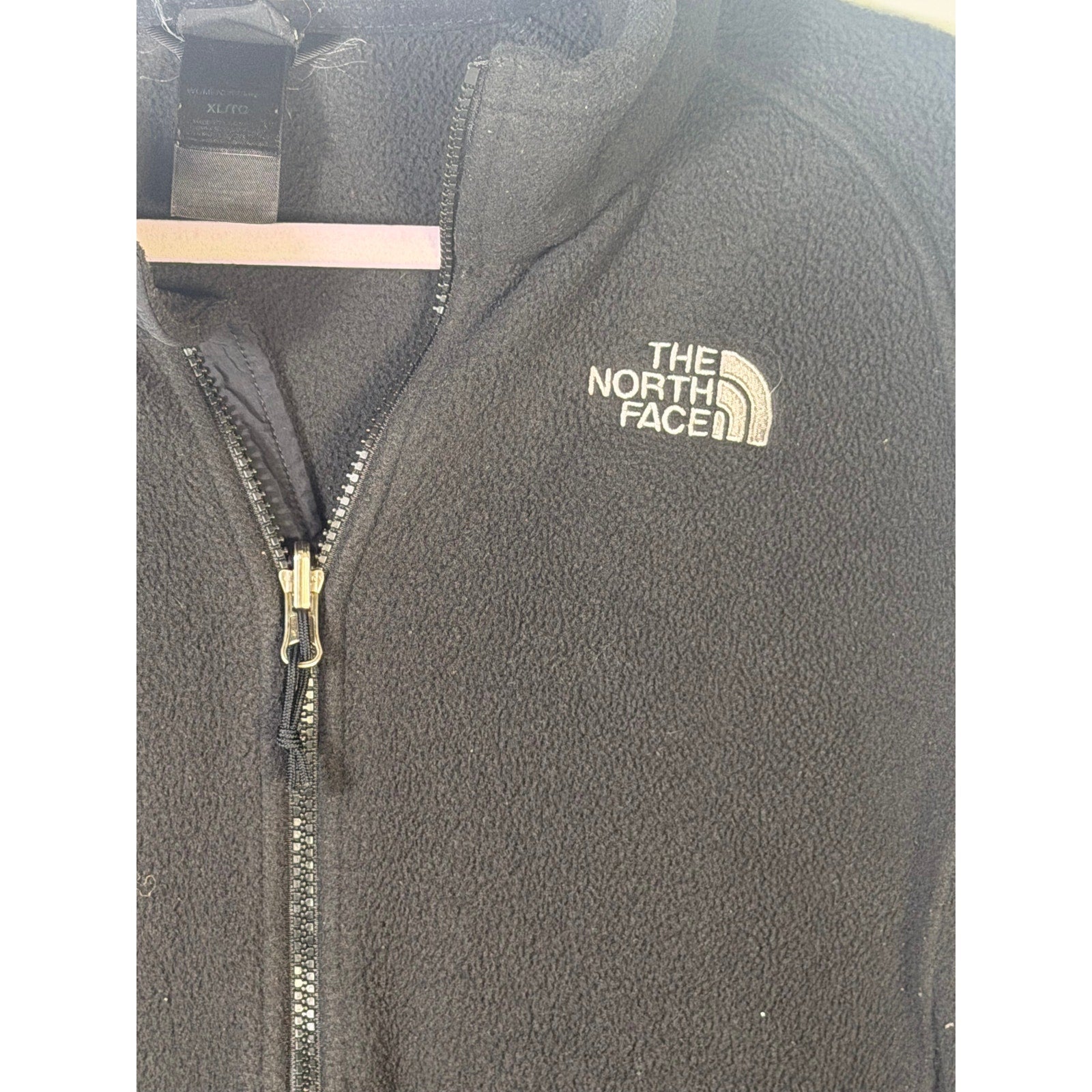 The North Face women's black full-zip fleece jacket with outdoor logo, featuring a cozy fleece texture and a full front zipper.