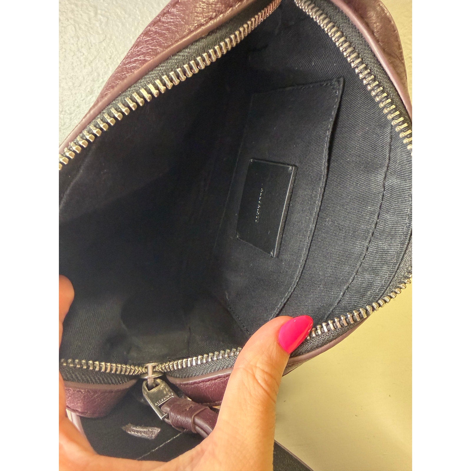 AllSaints women's burgundy pebbled leather camera crossbody handbag with adjustable strap and compact design.