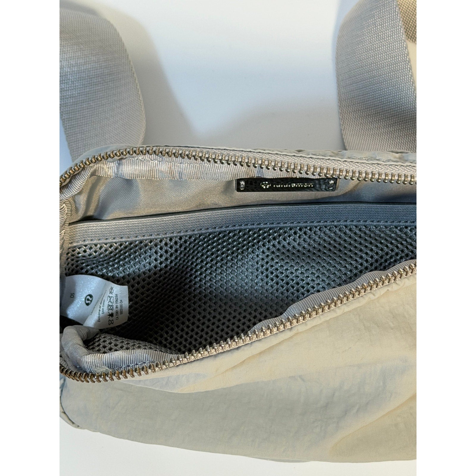 Light gray Lululemon Everywhere Belt Bag, a crossbody waist pack with a sleek handbag design and adjustable strap.