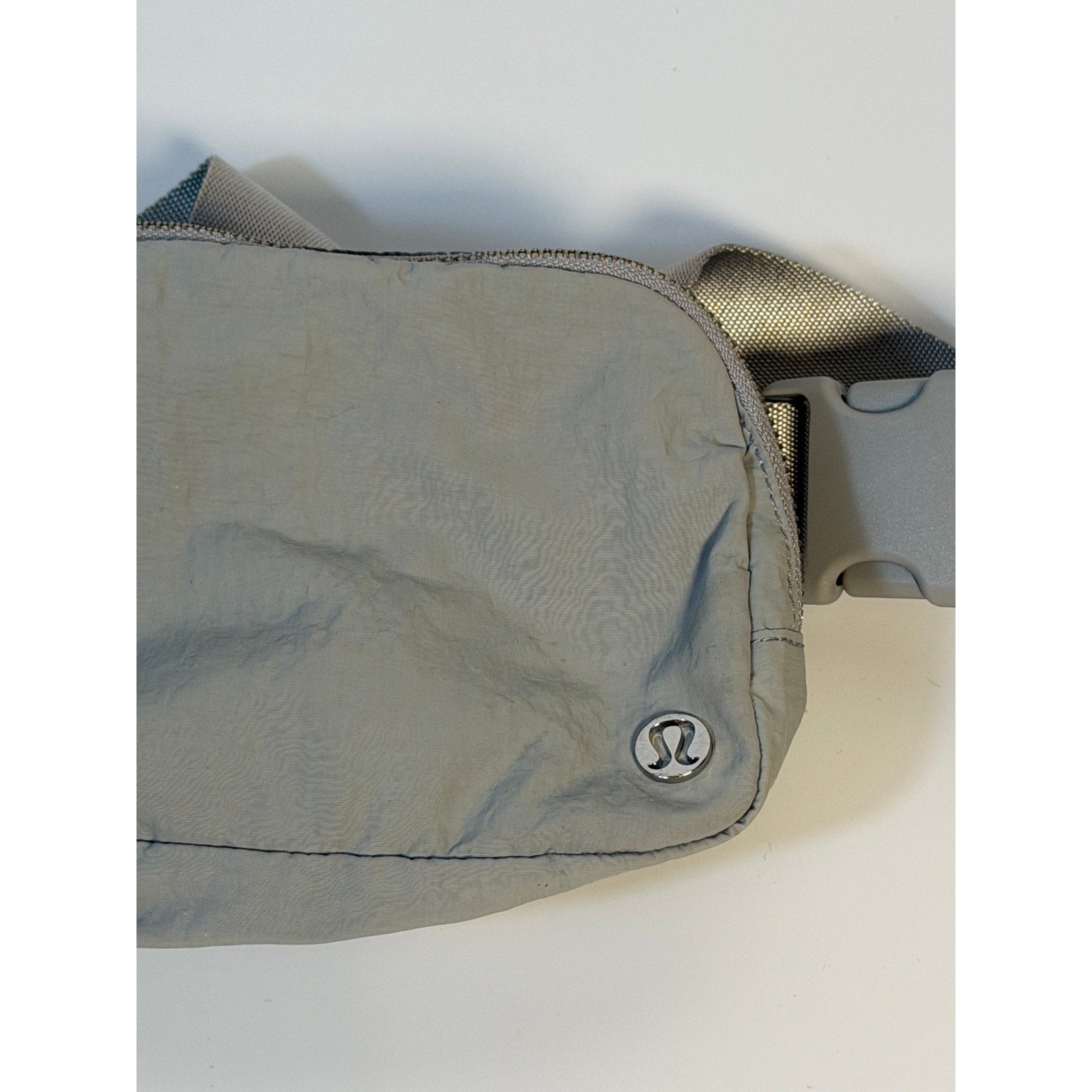 Lululemon Everywhere Belt Bag in light gray, a crossbody waist pack with adjustable strap and sleek handbag design.