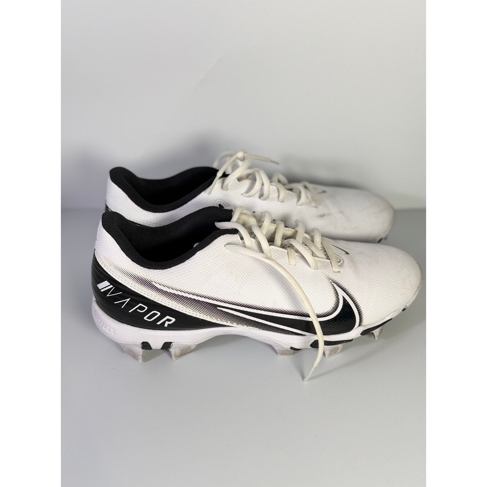 Nike Vapor football cleats in white and black, men's size 8.5 US, with cleat studs and Nike branding visible.