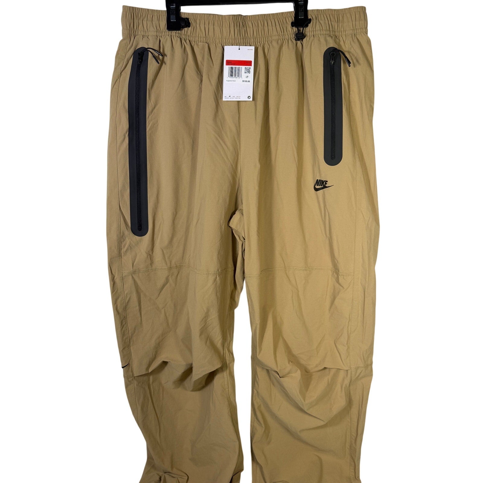 Nike Tech men's oversized woven parachute beige pants, size L, showing relaxed fit with woven fabric and drawstring waist.
