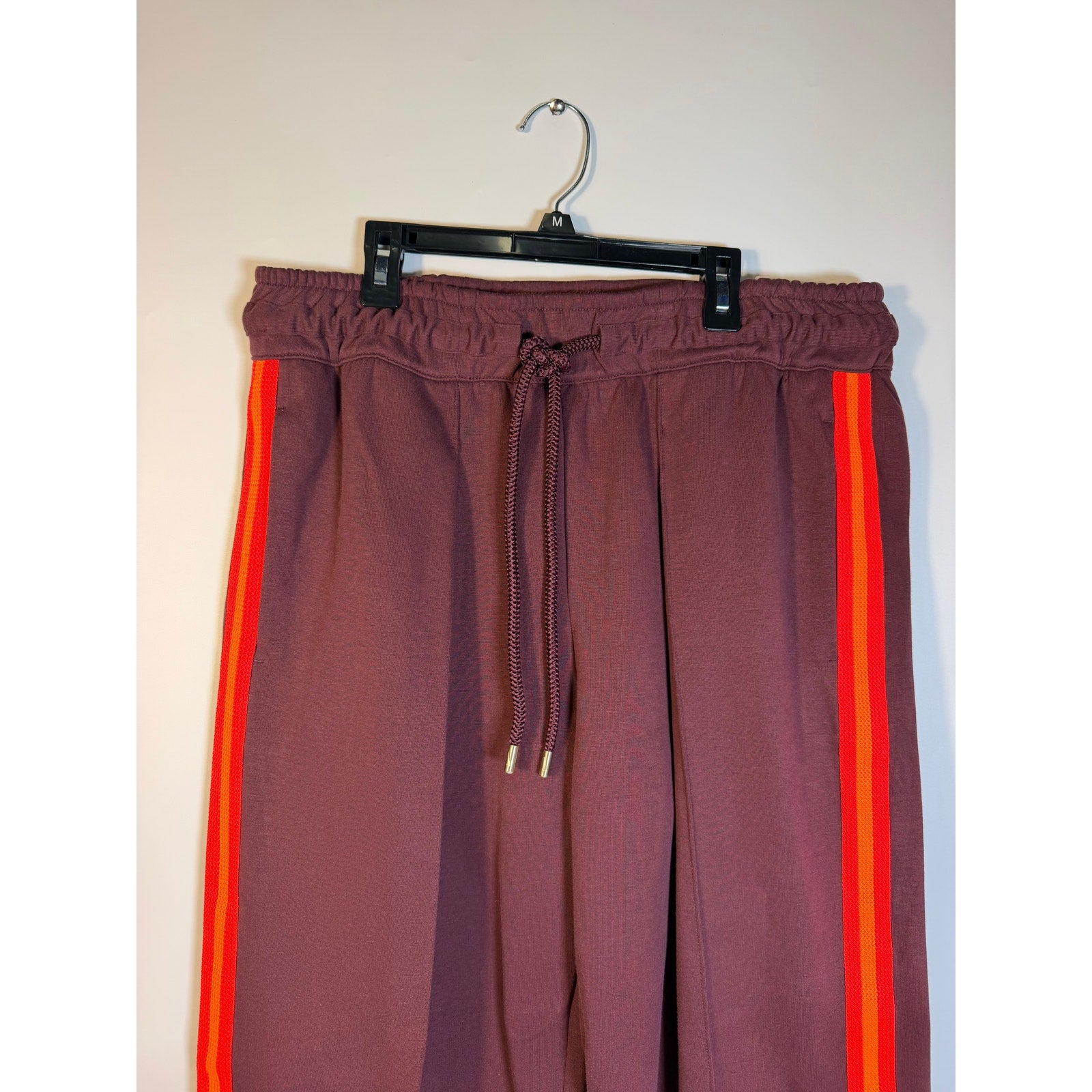 Nike NOCTA men's brown and orange striped fleece track pants with open hems, size large, featuring a comfortable and sporty design.
