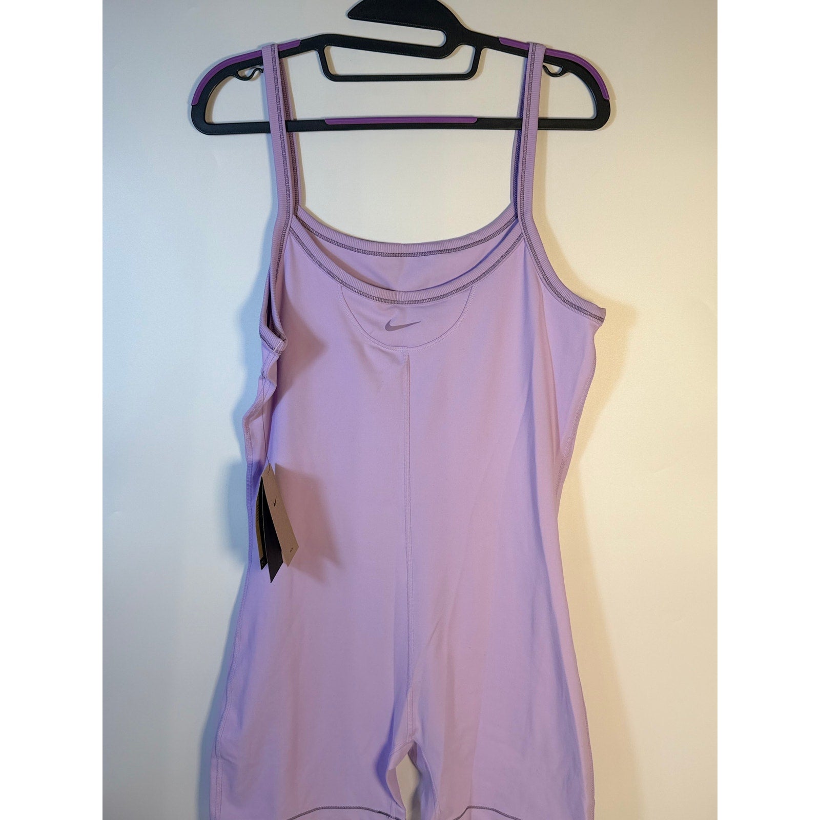 Nike women's lavender Dri-FIT training romper bodysuit, size large, shown on a hanger with a close-up of fabric and design details.