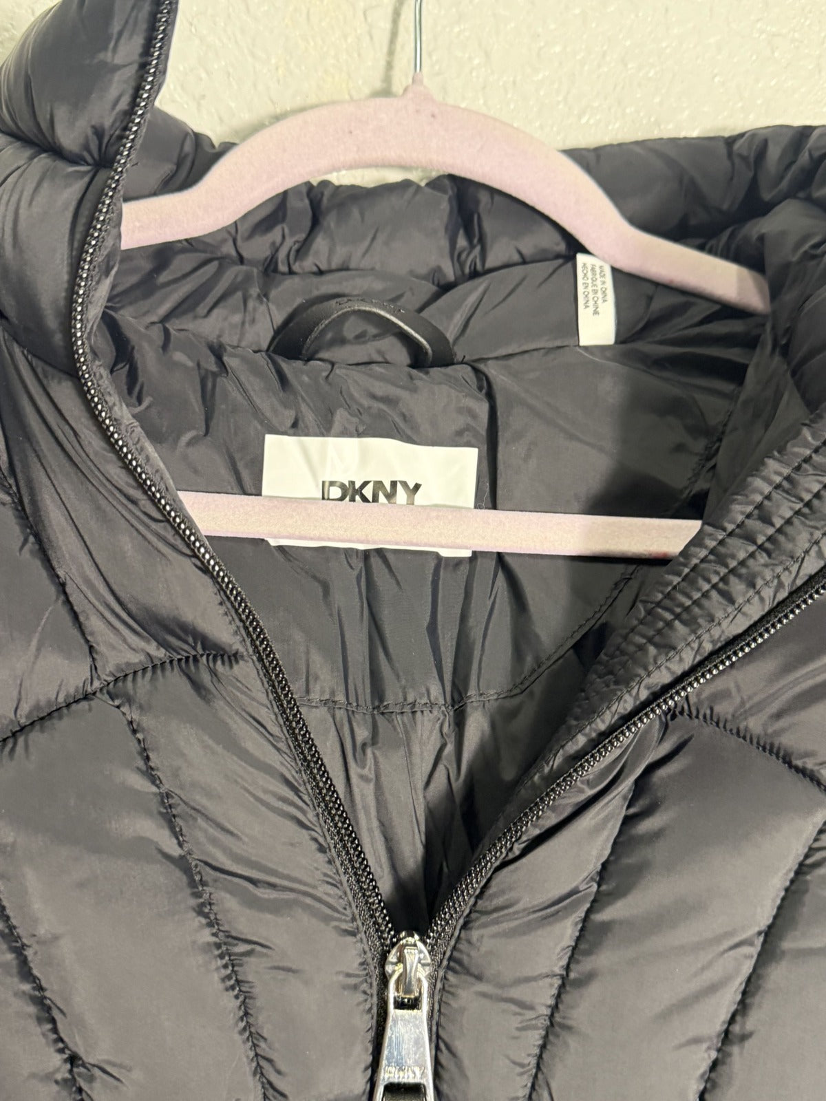 Black DKNY women's hooded quilted puffer jacket with a fitted design, featuring a front zipper and cozy hood.