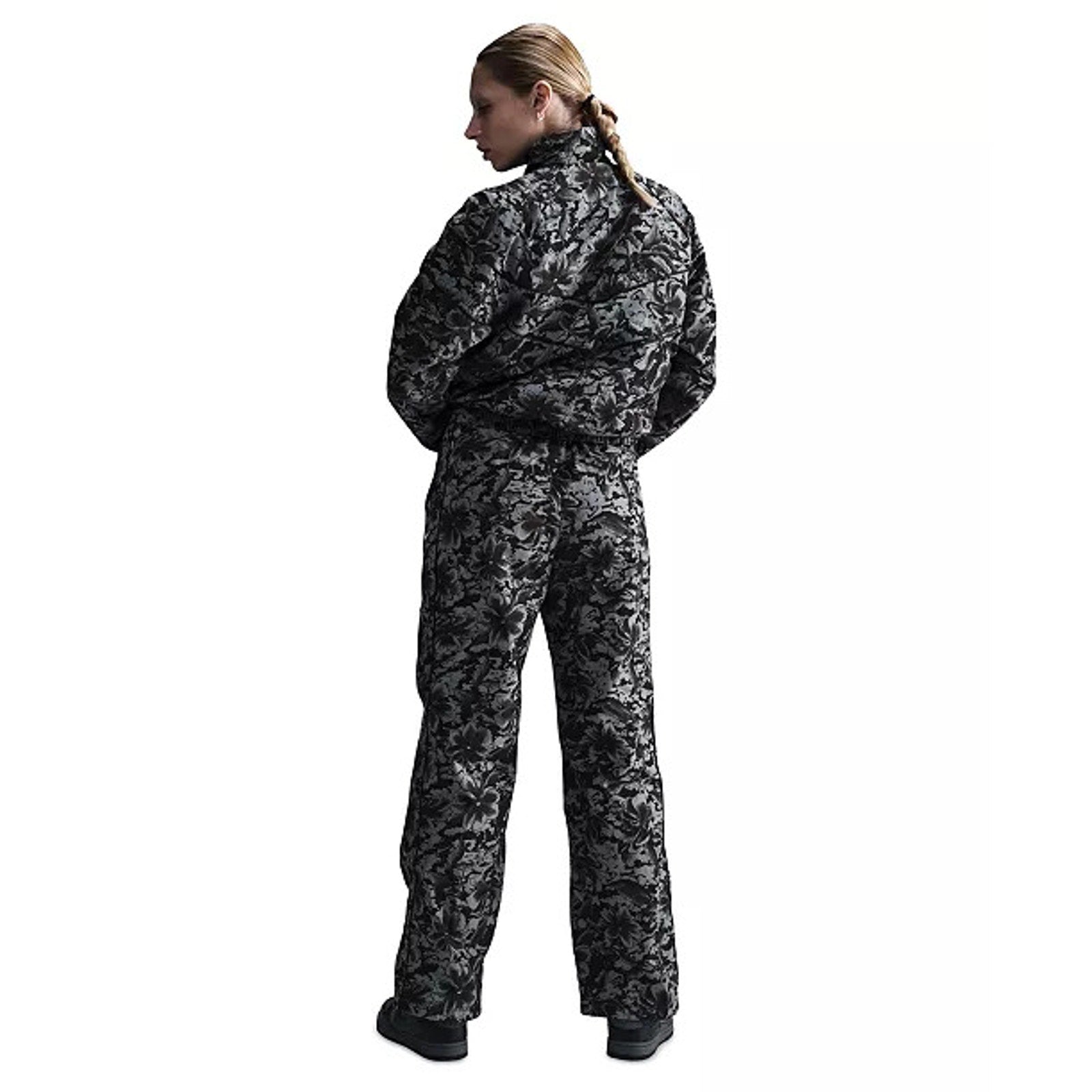 Nike Sportswear women's floral wide-leg track pants in black and gray with high-rise fit, shown laid flat.