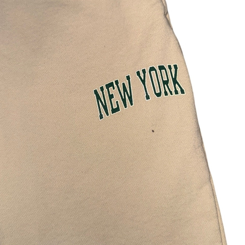 Cream beige Brandy Melville New York graphic jogger sweatpants with elastic waistband, size L, casual and comfortable athletic wear.
