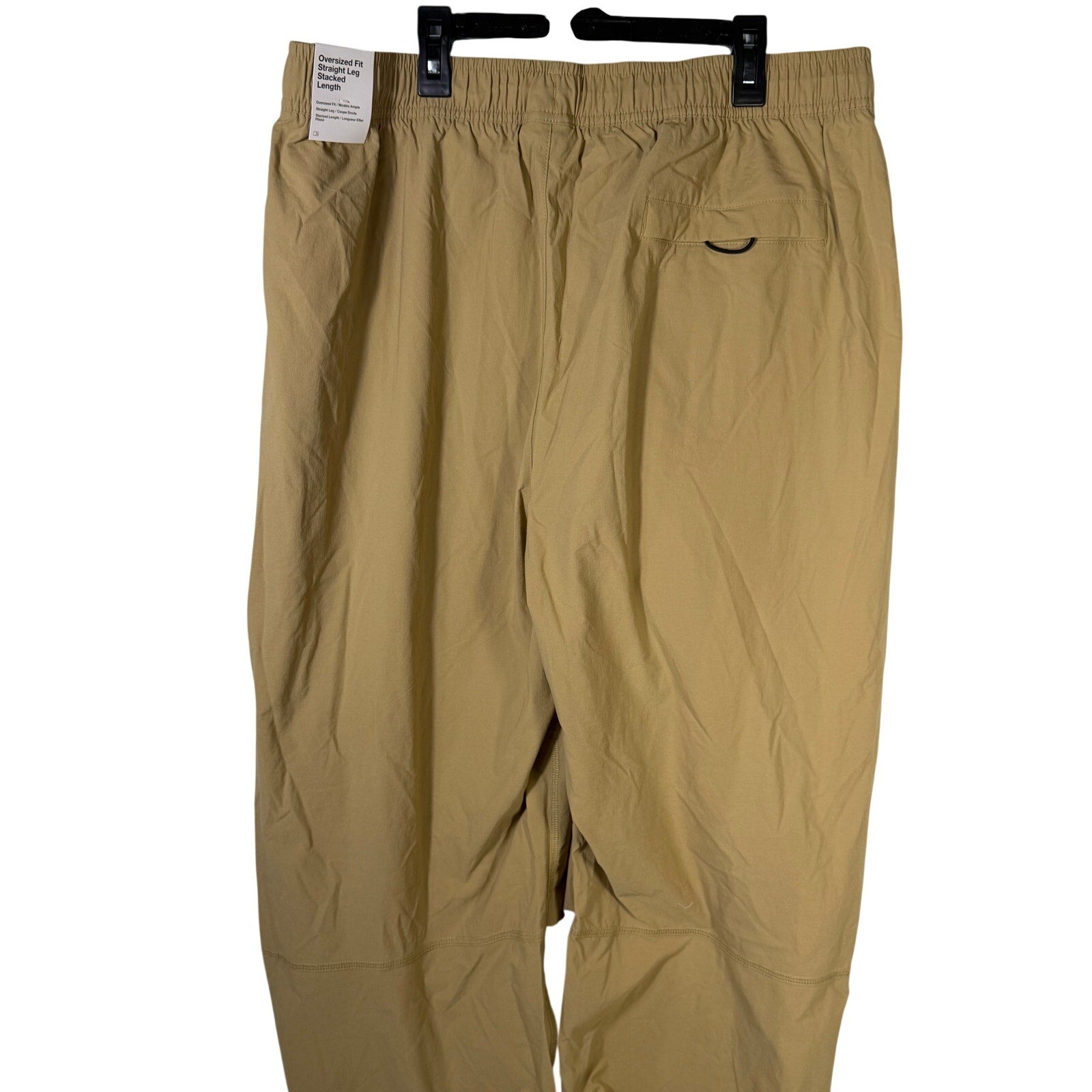 Nike Tech men's woven oversized parachute beige pants, size L, displayed flat showing the relaxed fit and lightweight fabric.