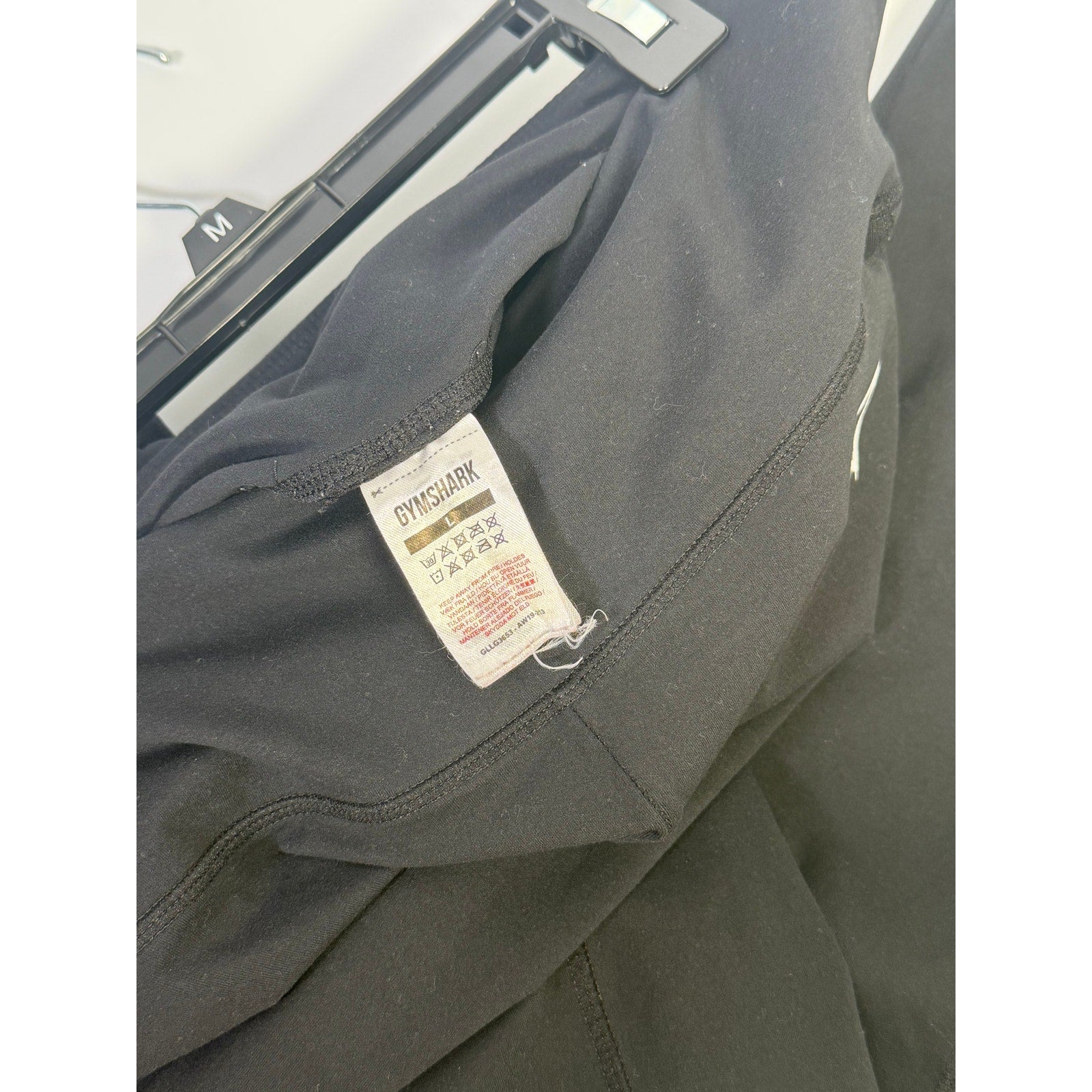Black Gymshark women's high-waisted leggings with side pockets, size L, showing a close-up of the fitted, stretchy fabric.
