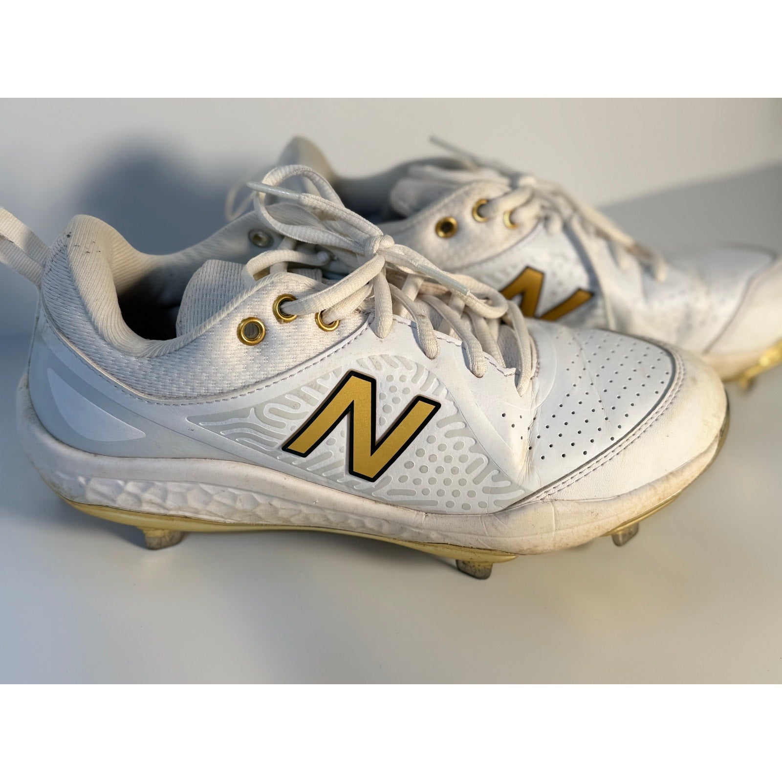 New Balance FuelCell COMPv2 baseball cleats in white and gold for men's size 7.5 with metal cleats and athletic design.