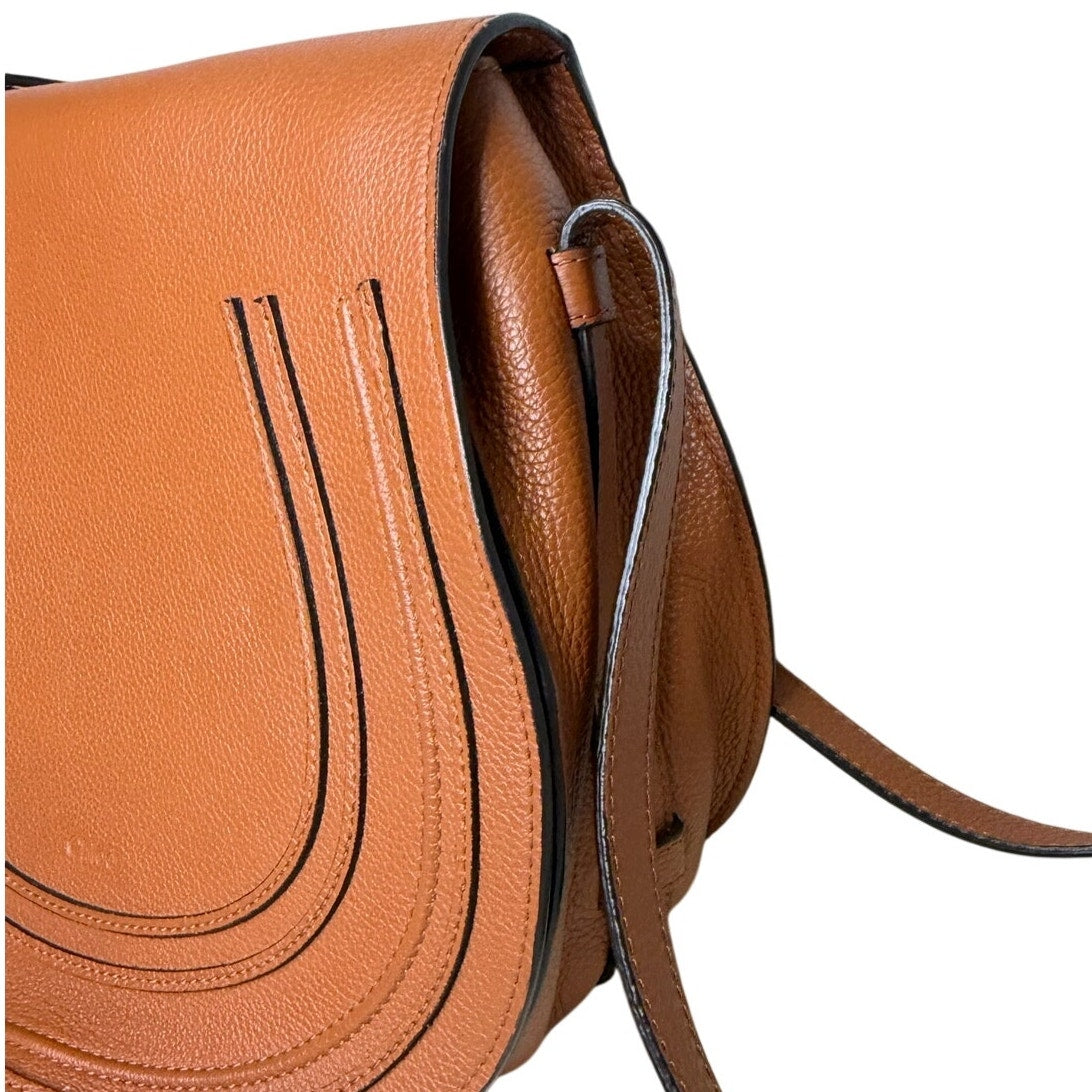 Chloé Marcie medium saddle crossbody handbag in grained calfskin leather with gold hardware, brown color, and adjustable strap.