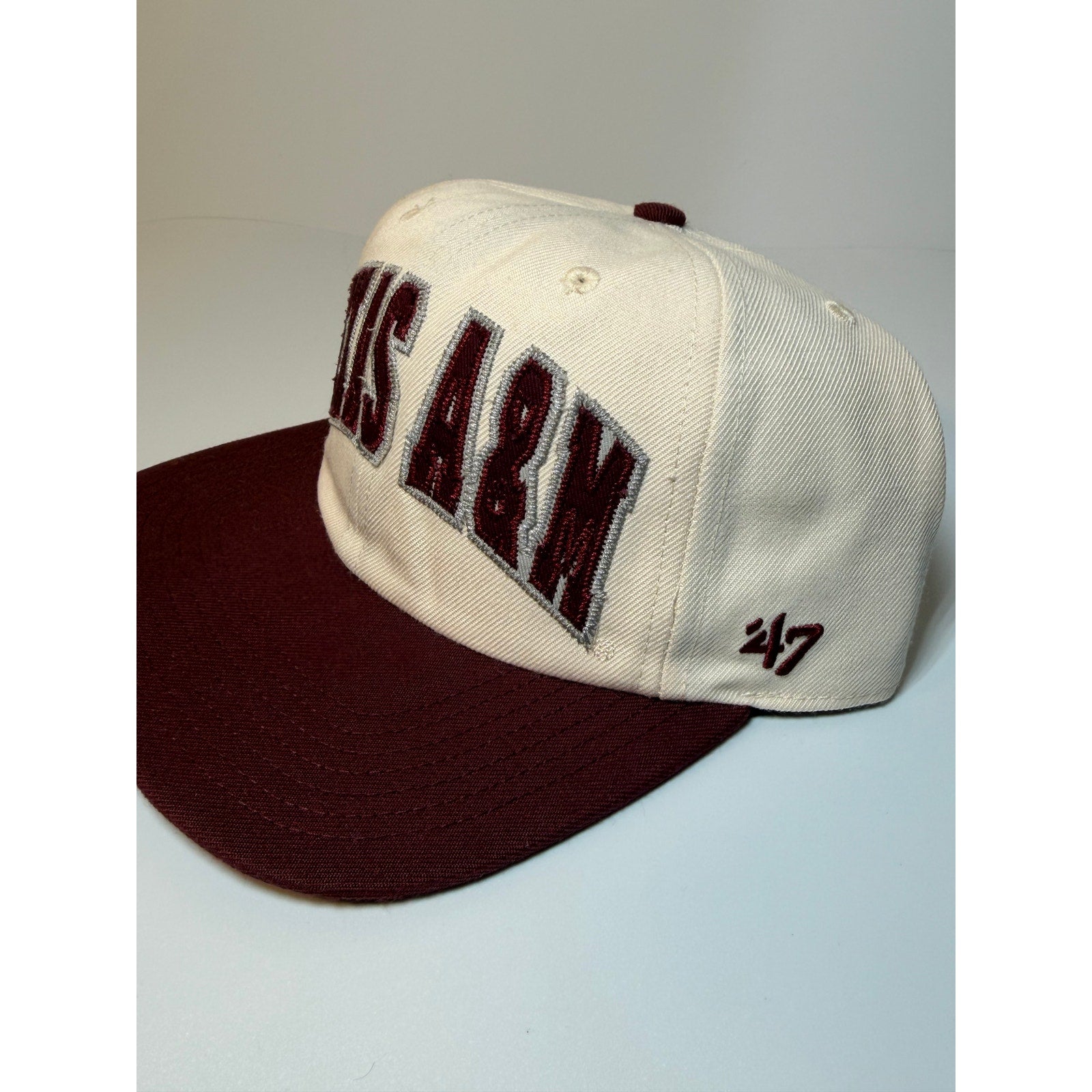 47 Brand Texas A&M Aggies snapback hat in cream and maroon with adjustable strap, featuring team logo and classic baseball cap design.