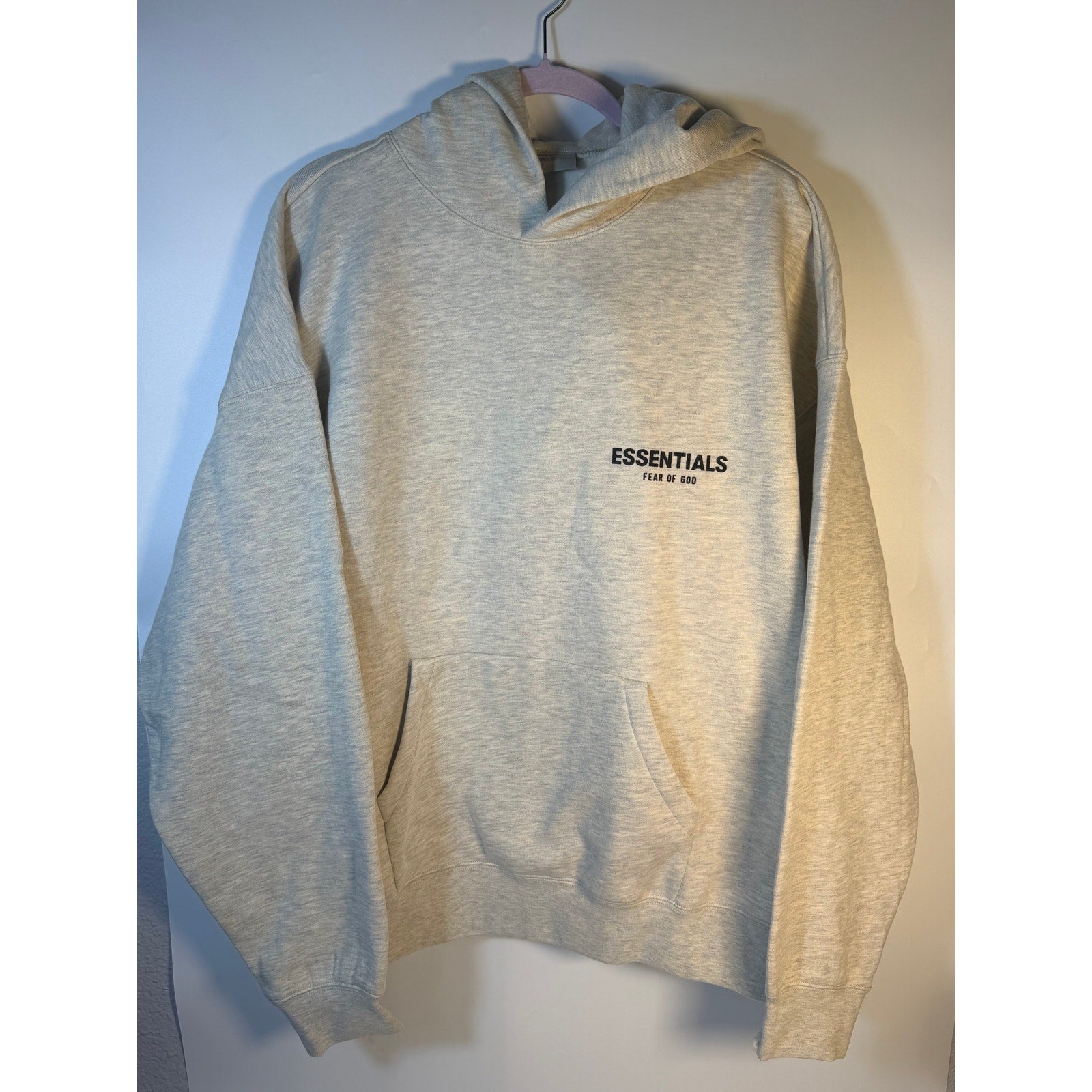 Fear of God ESSENTIALS men's light oatmeal pullover hoodie with logo detail, casual sweatshirt, front view.