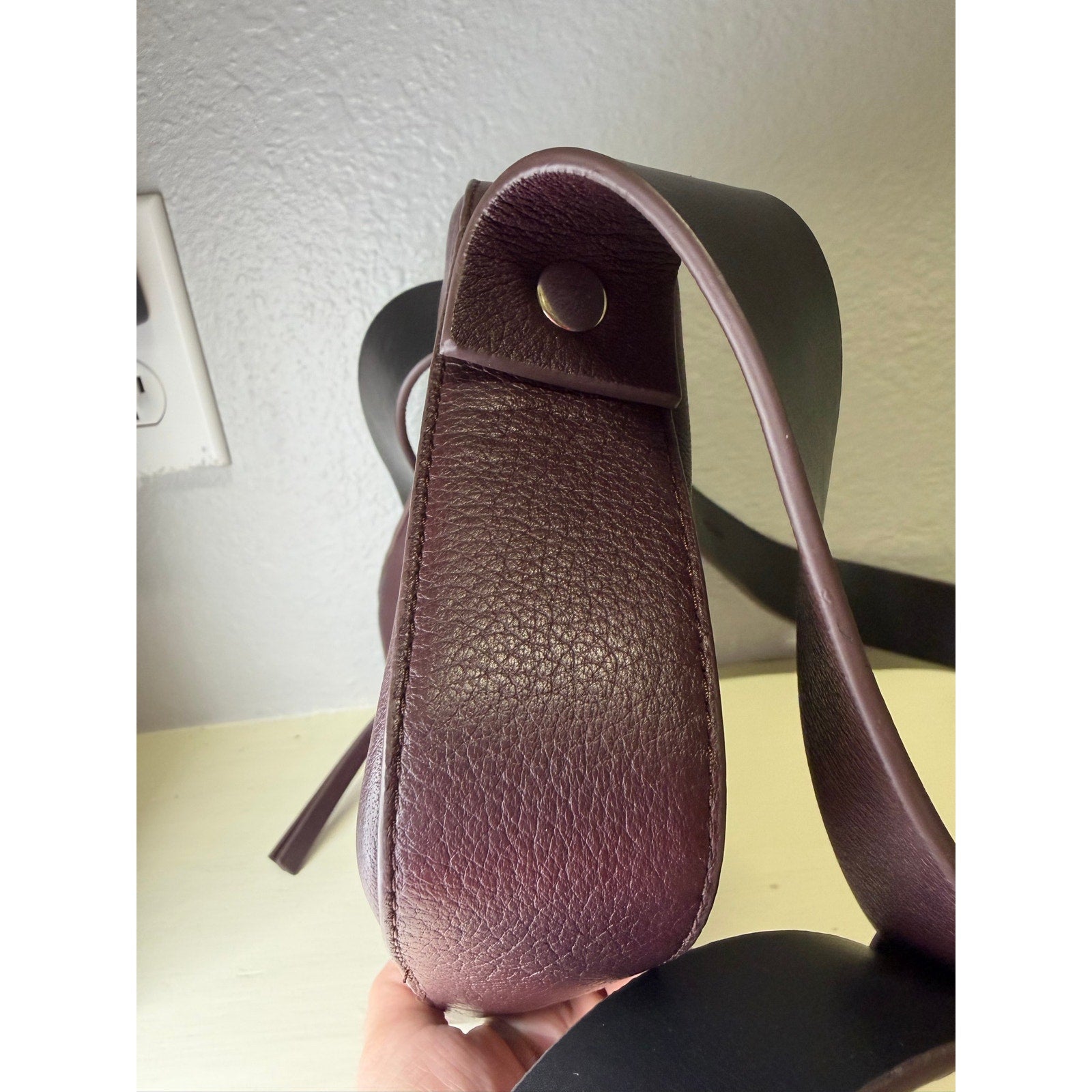 AllSaints women's burgundy pebbled leather camera crossbody bag with adjustable strap on a white background.