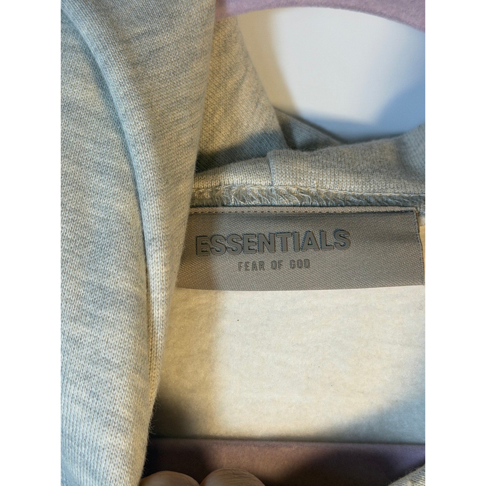 Fear of God ESSENTIALS men's light oatmeal pullover hoodie with logo, soft fabric, and relaxed fit.