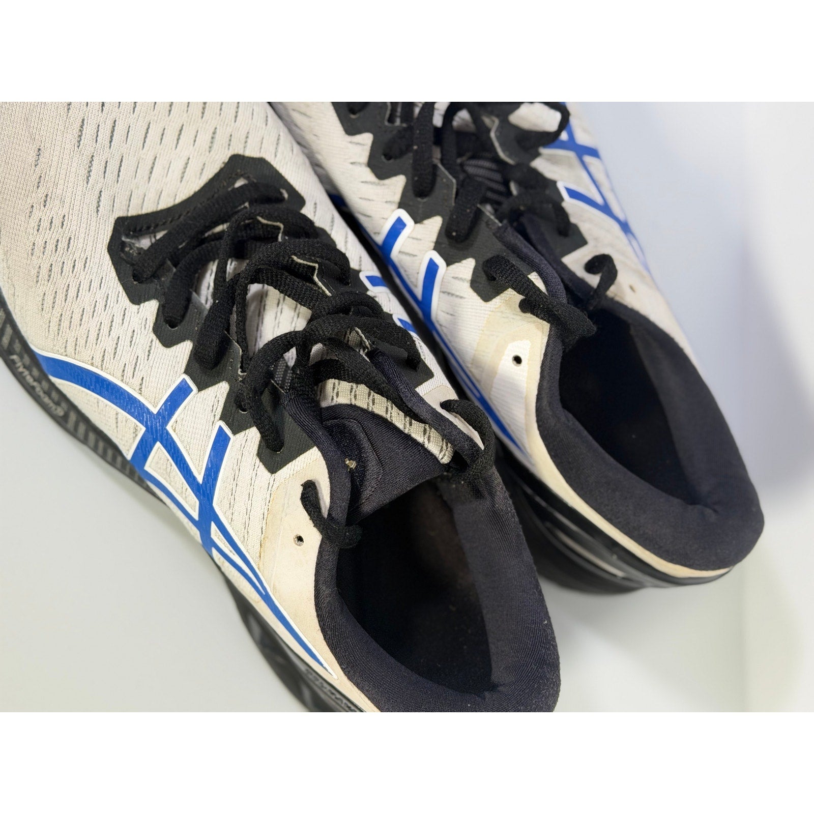 Men's ASICS Gel Cumulus 24 running sneakers in white, blue, and black with breathable mesh and cushioned sole for comfort.