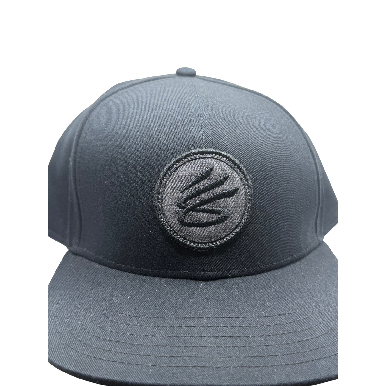 Curry Brand black snapback hat, adjustable basketball cap, front view showing logo and flat brim, one size fits most