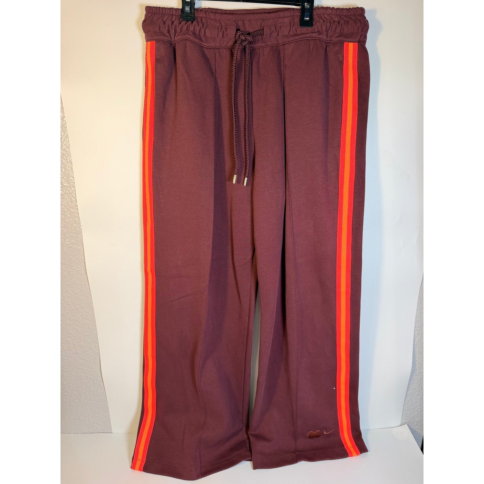 Nike NOCTA men's fleece track pants with open hem, brown and orange striped design, size large, comfortable athletic pants.