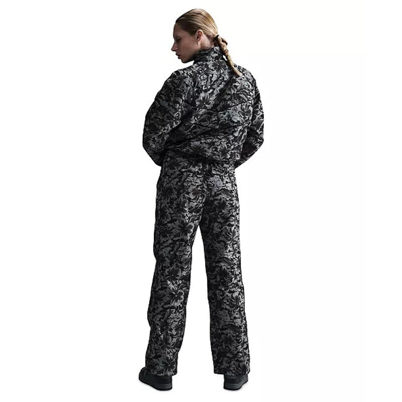 Nike Sportswear women's floral wide-leg track pants in black and gray, featuring a relaxed fit and floral pattern.