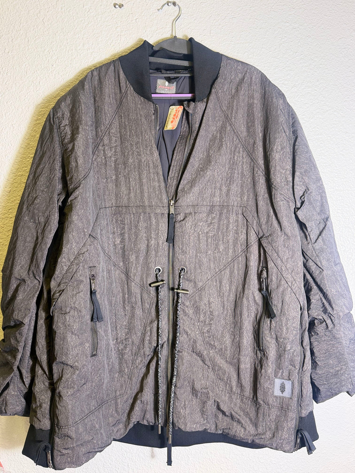 Gray Free People Movement oversized bomber jacket for women, shown on a hanger with front view and detailed fabric texture.