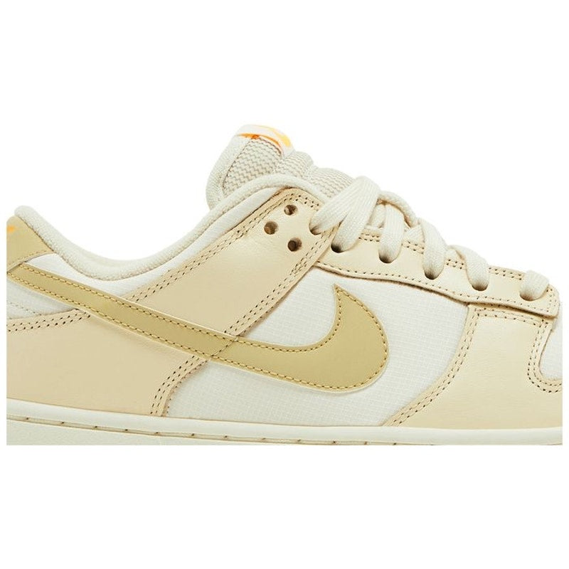 Nike Dunk Low women's sneakers in Team Gold and White, featuring a low-top design with gold accents and white leather overlays.
