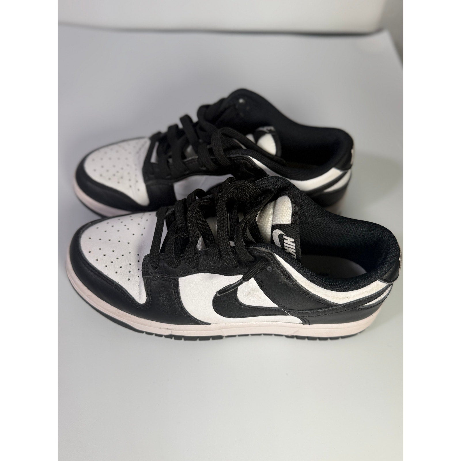 Nike Dunk Low Panda youth sneakers in black and white with a low-top design, featuring Nike branding and classic color blocking.